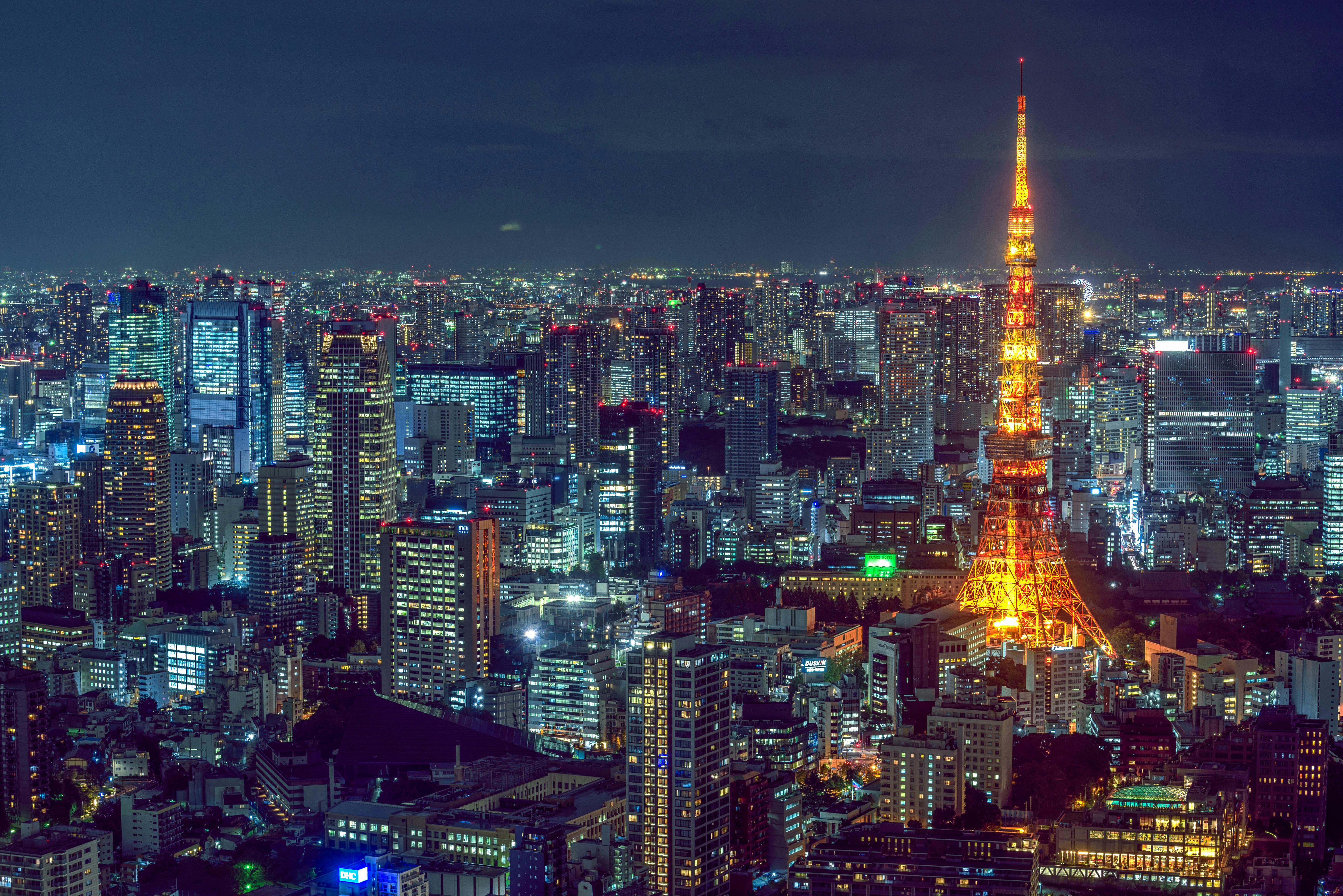 Tokyo skyline at night featuring the illuminated Tokyo Tower in the foreground against a backdrop of city lights