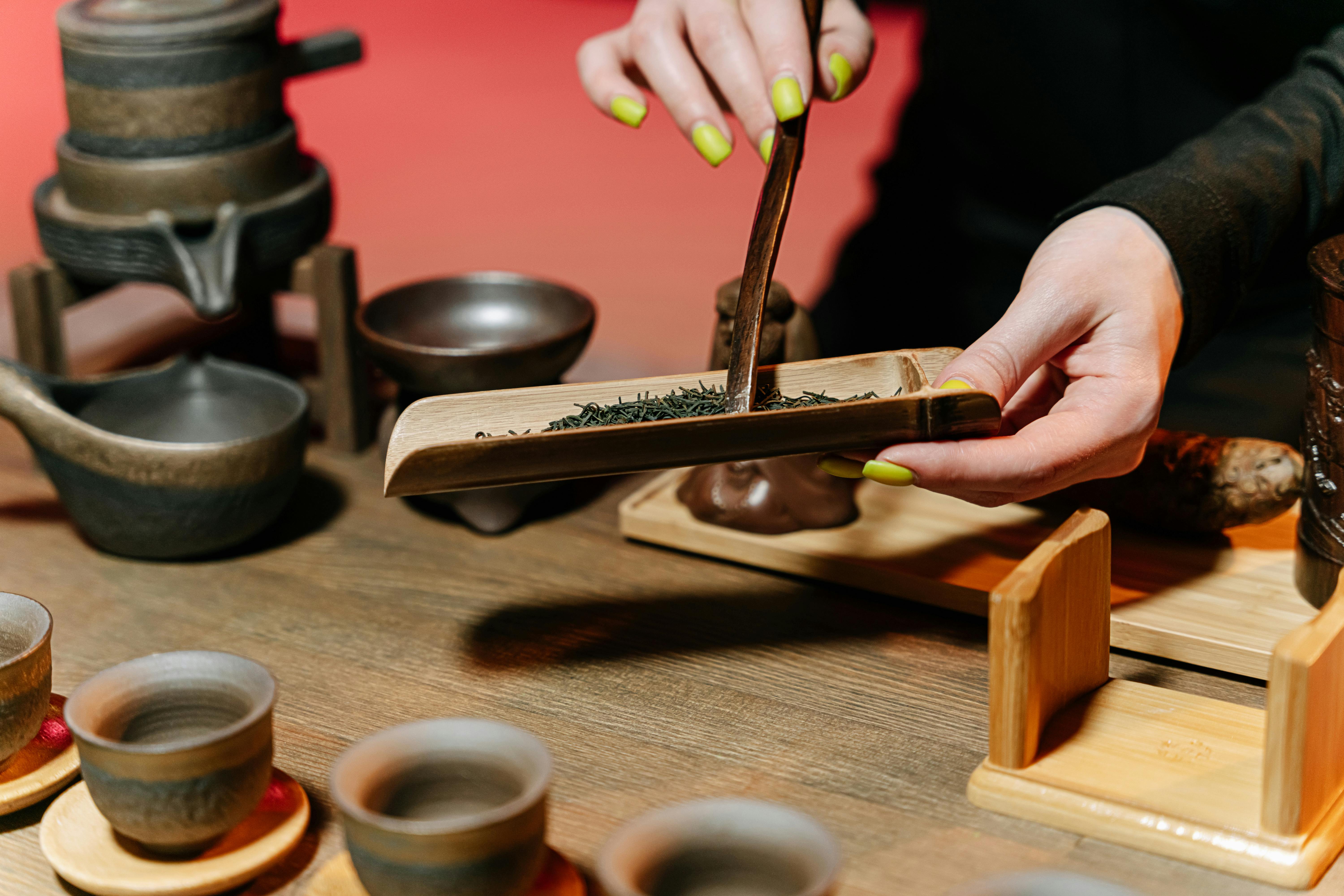 A person pours steaming tea from a teapot into a delicate cup, creating a warm and inviting scene