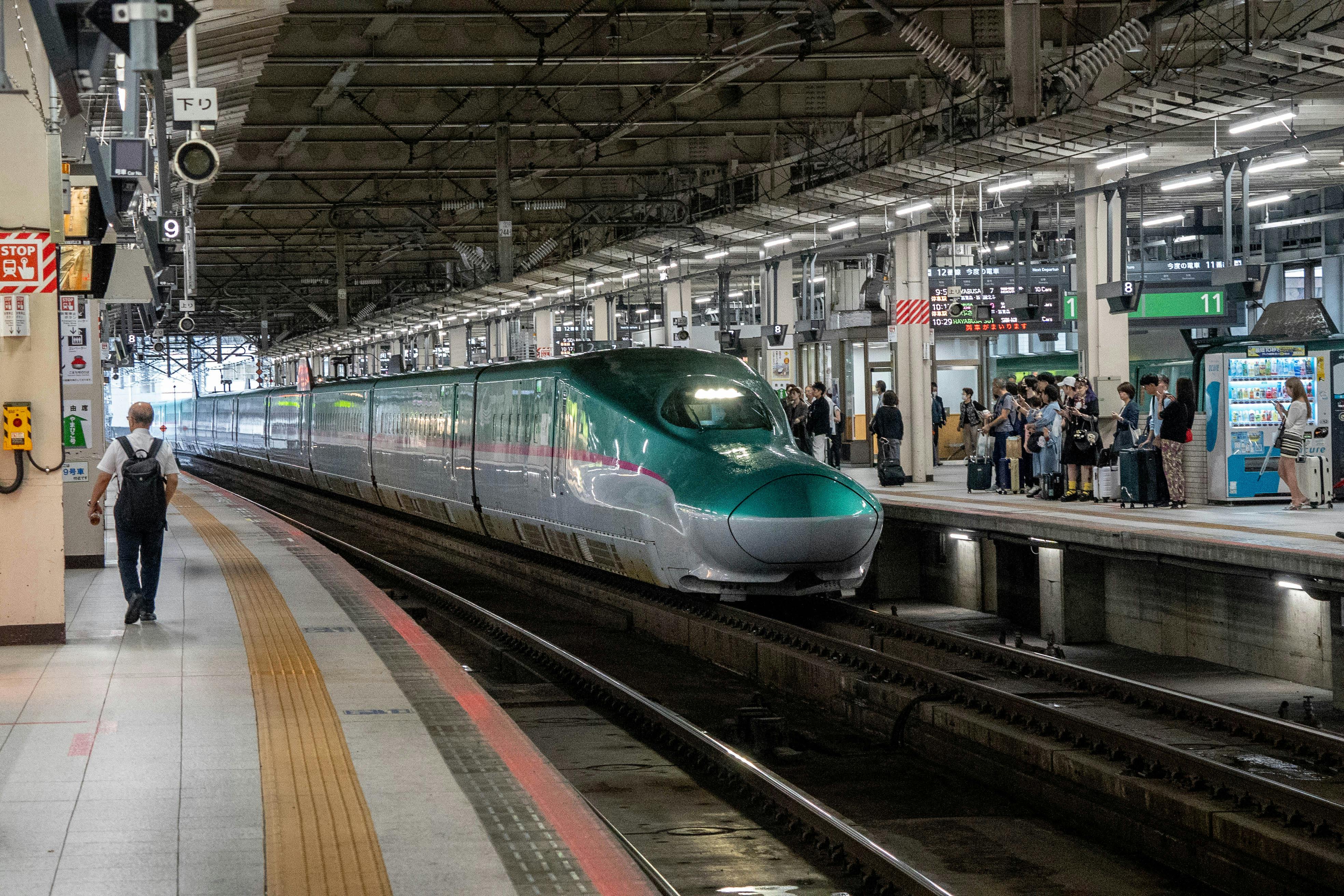 A green and white train approaches the station, ready to stop for passengers