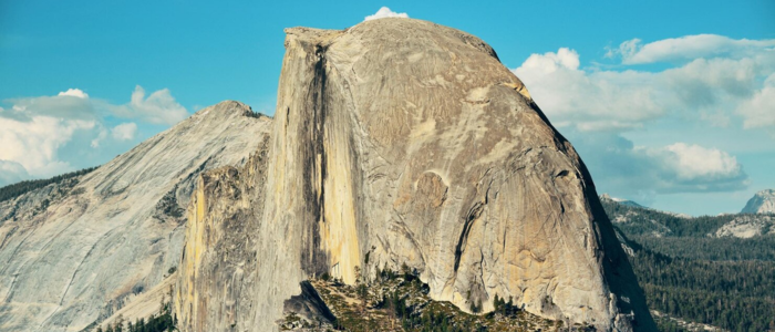 Half Dome rises majestically in Yosemite National Park, California, showcasing its iconic granite face against a clear sky.