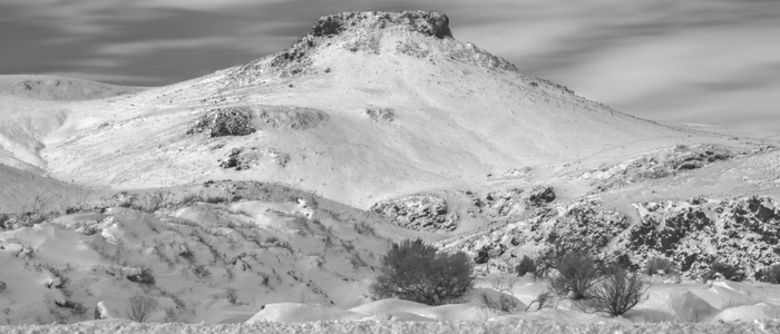 Black and white photo of a snow-covered mountain, showcasing its majestic peaks and serene winter landscape.