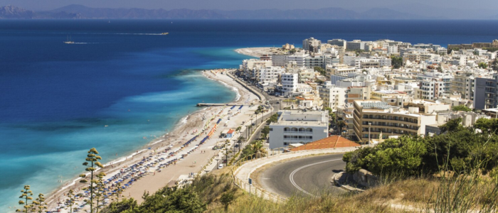 Rhodes coastline with sandy beach, turquoise sea, and seaside town buildings